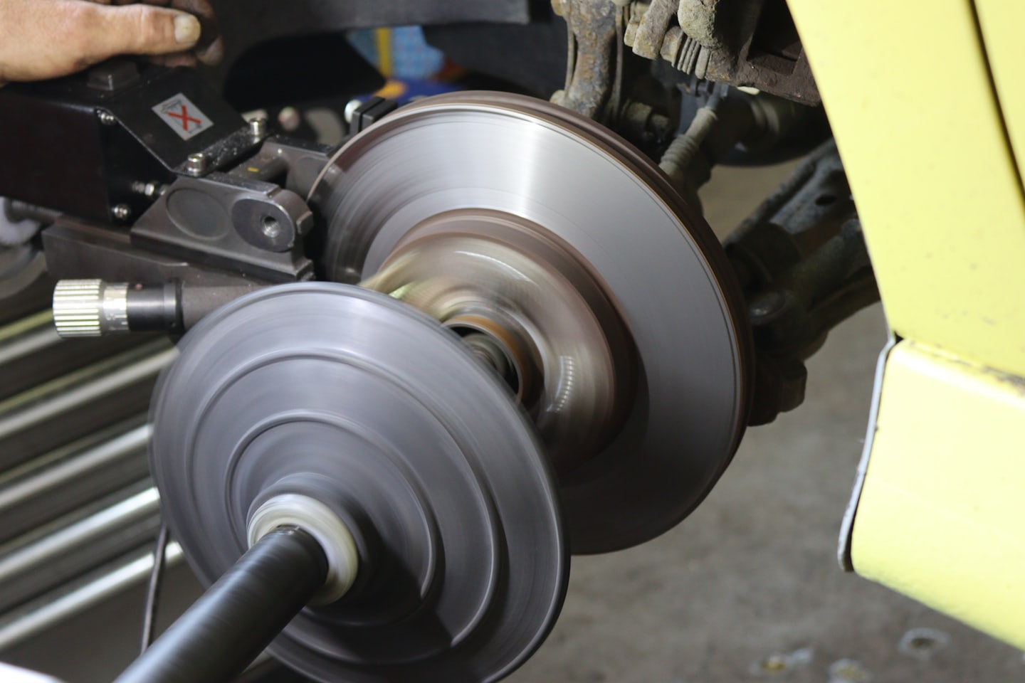Mechaniker bearbeitet Bremsscheibe eines Autos mit einer Bremsscheiben-Drehmaschine.