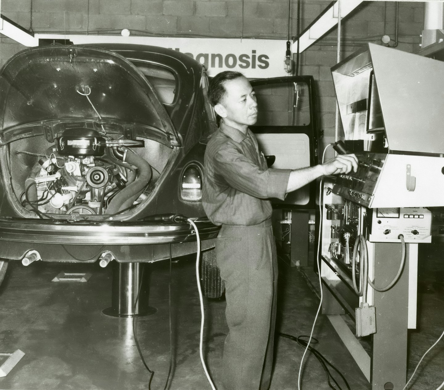 Mechaniker nutzt Diagnosegeräte an einem Oldtimer-Volkswagen-Käfer.